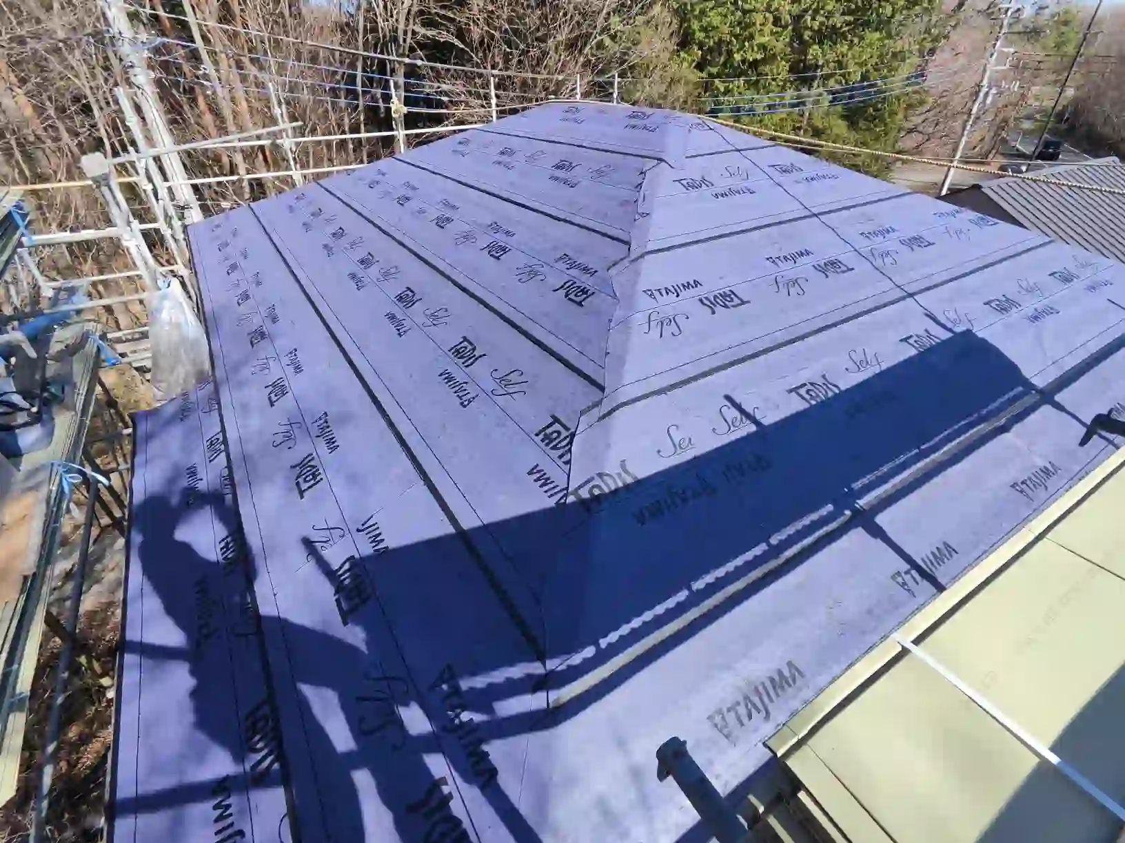 粘着式の下張り材を屋根全面に張っていく。