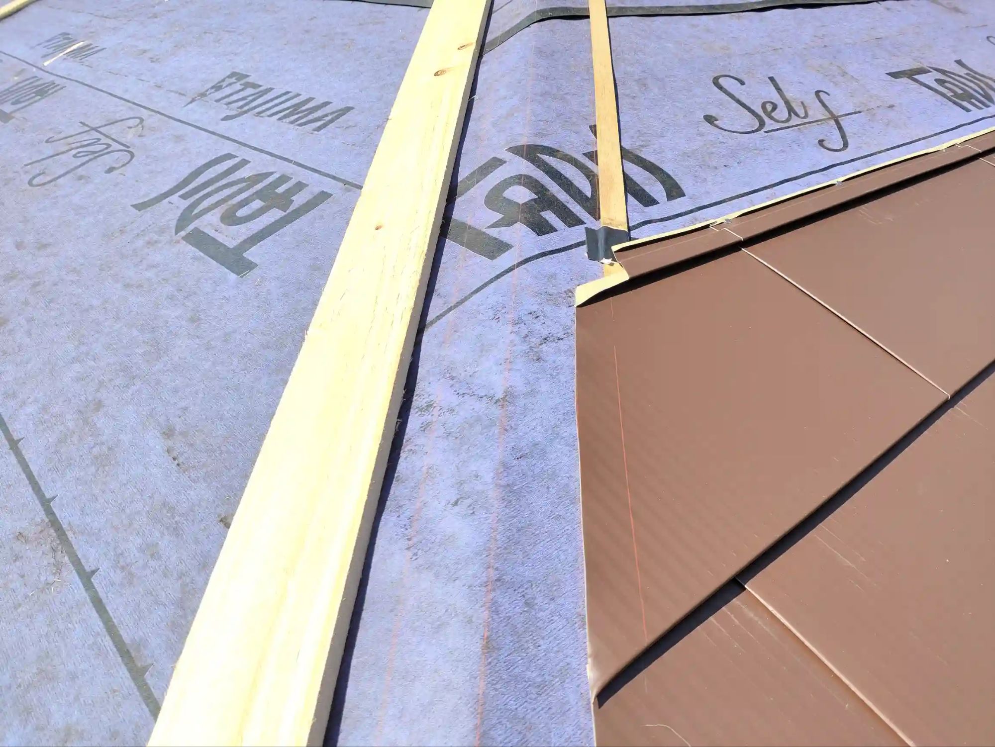 屋根材施工、隅棟の部分の拡大。ガルバ鋼板をラインに沿ってカットして張っていく。